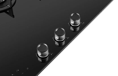 Close-up of a black glass cooktop with three knobs on a white background